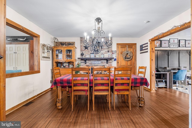 dining room featuring a chandelier, wood-type flooring, visible vents, and baseboards