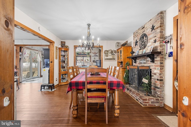 dining space featuring a fireplace, a notable chandelier, and hardwood / wood-style floors