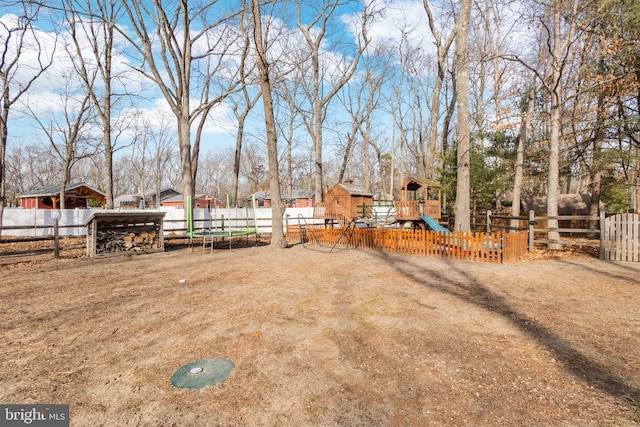 view of yard with a trampoline, fence, and a playground