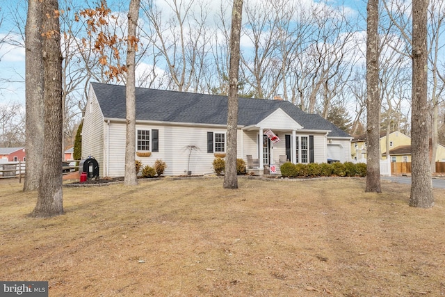 ranch-style home featuring a chimney, a shingled roof, an attached garage, fence, and a front lawn