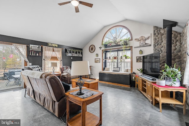 living room with a wood stove, ceiling fan, and vaulted ceiling