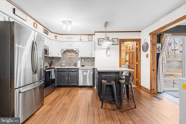 kitchen with a breakfast bar, stainless steel appliances, light countertops, light wood-type flooring, and white cabinetry