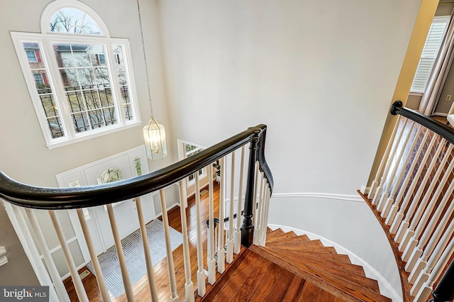 stairway with a notable chandelier and wood finished floors