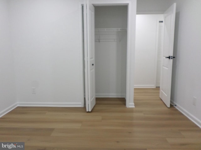 unfurnished bedroom featuring a closet, baseboards, and wood finished floors