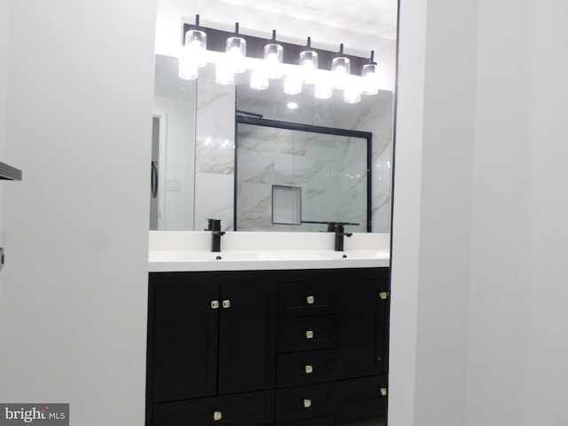 bathroom featuring double vanity, a marble finish shower, and a sink