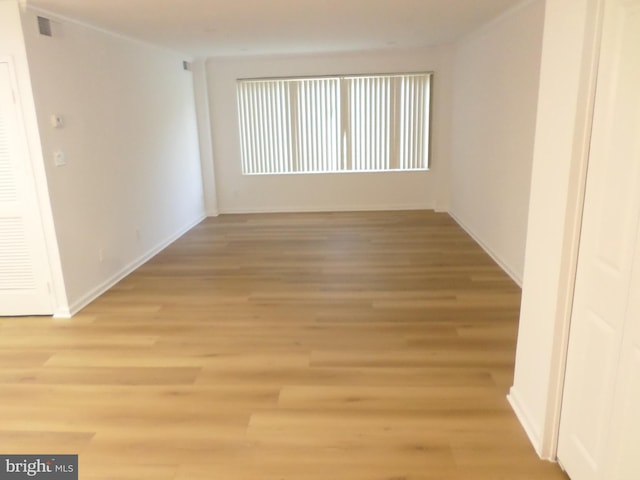 spare room featuring baseboards and light wood finished floors