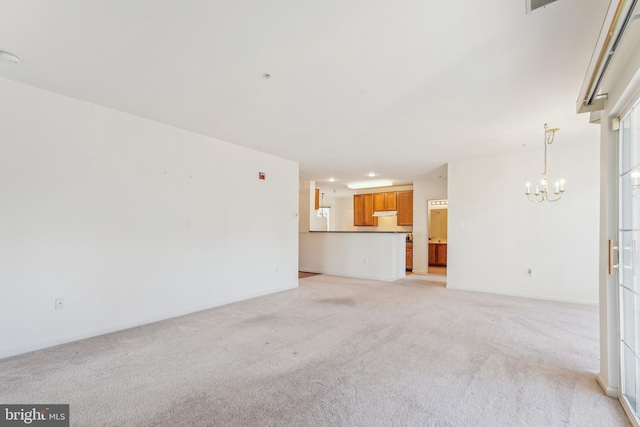 unfurnished living room featuring light colored carpet, baseboards, and a chandelier