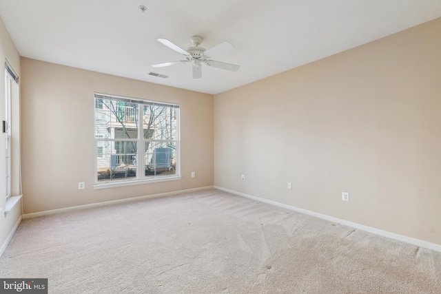 empty room with visible vents, light colored carpet, baseboards, and ceiling fan