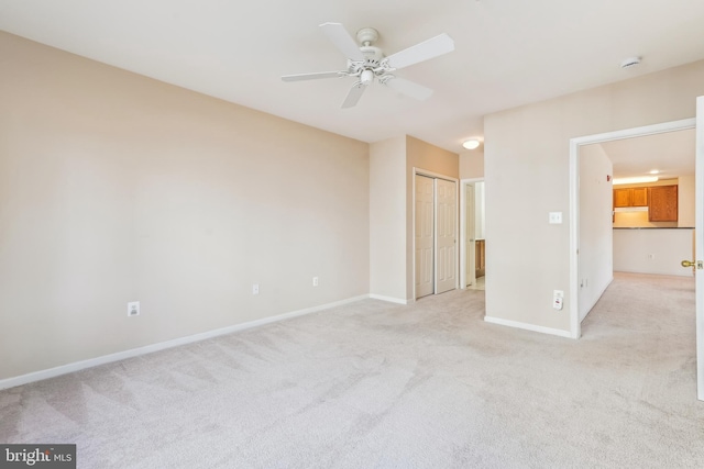 unfurnished bedroom featuring light colored carpet, baseboards, and ceiling fan