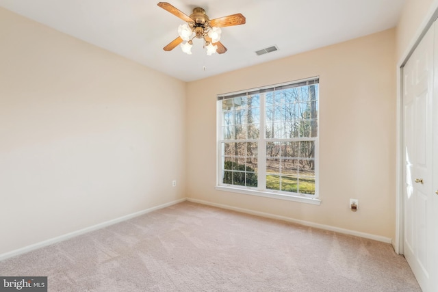 unfurnished room with visible vents, light carpet, baseboards, and a ceiling fan