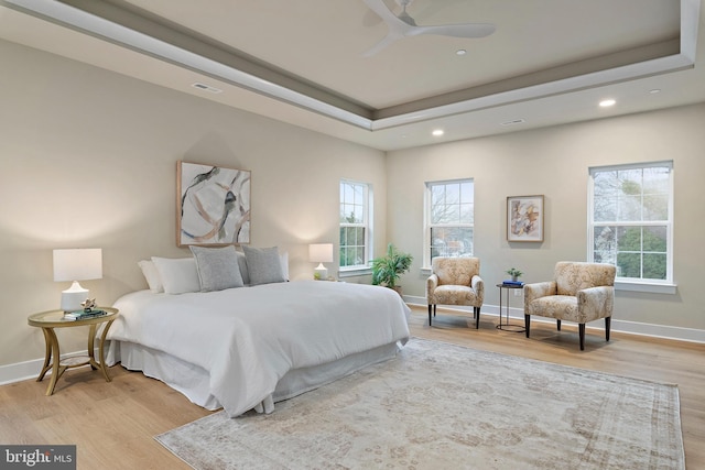 bedroom featuring a tray ceiling, wood finished floors, and baseboards