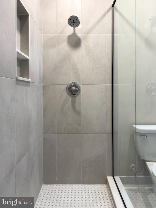 full bathroom with a tile shower and toilet