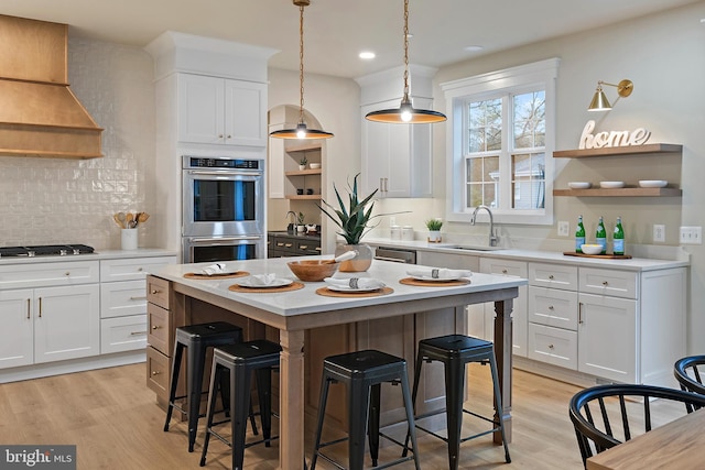 kitchen with stainless steel appliances, premium range hood, open shelves, and a sink