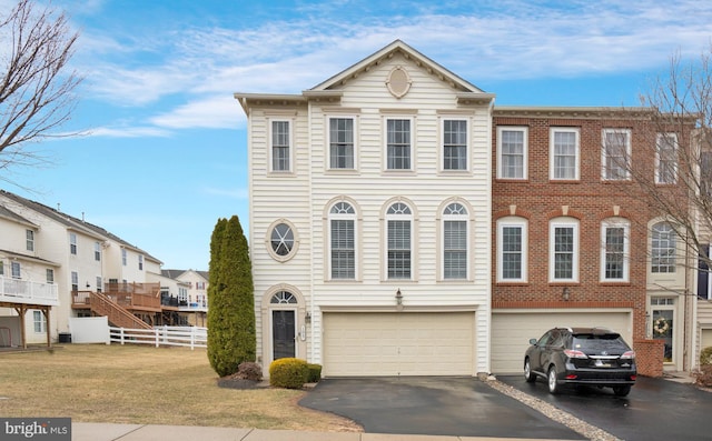 townhome / multi-family property featuring driveway, an attached garage, fence, and a front lawn