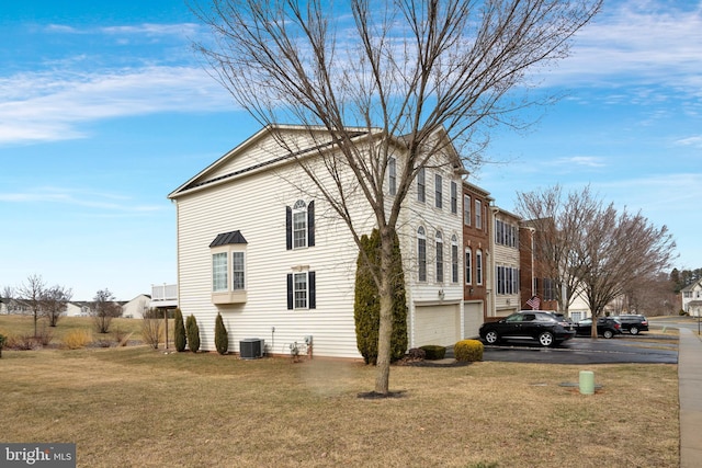 view of side of home with a garage, central AC, a lawn, and driveway