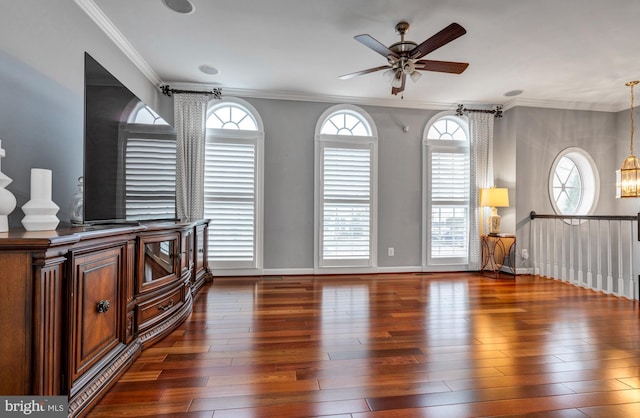 interior space with baseboards, ornamental molding, wood finished floors, and ceiling fan with notable chandelier