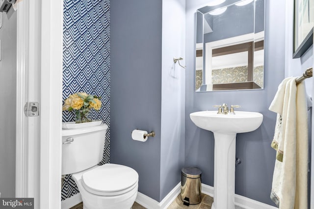 bathroom featuring toilet, baseboards, and a sink