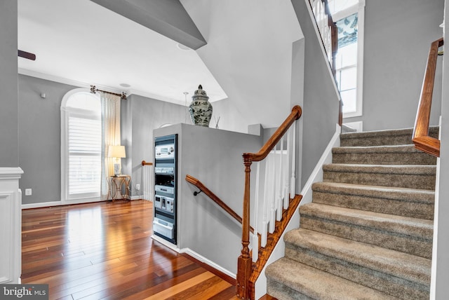 staircase featuring ornamental molding, wood-type flooring, and baseboards