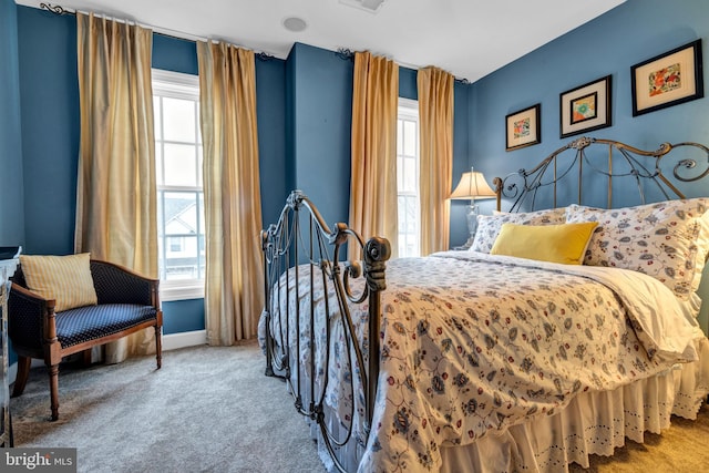 carpeted bedroom with visible vents, multiple windows, and baseboards