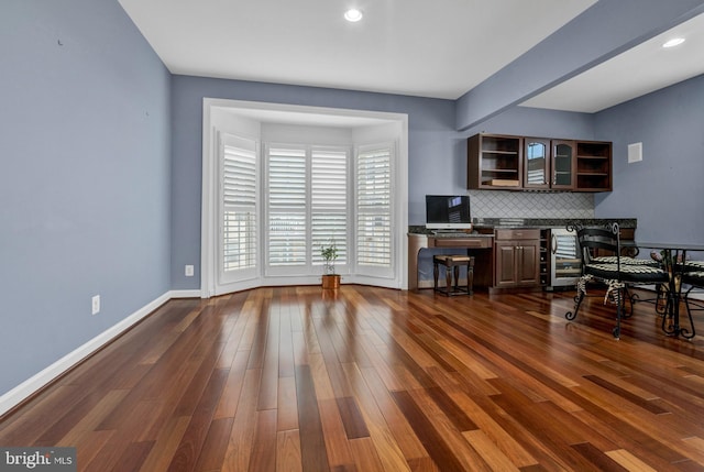 interior space featuring dark wood-style floors, beverage cooler, baseboards, and built in desk