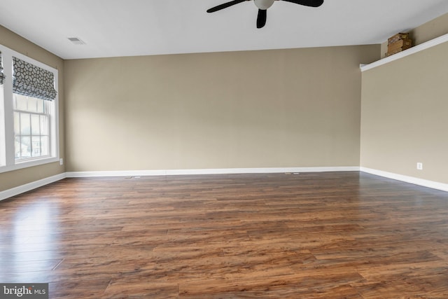 empty room featuring baseboards, visible vents, ceiling fan, and dark wood-type flooring