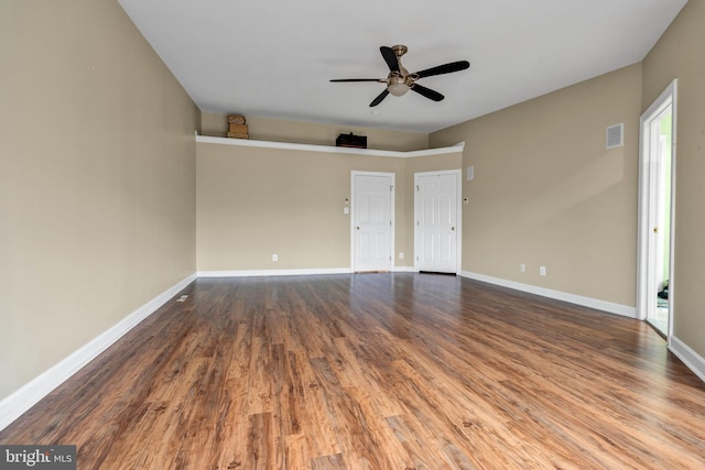 interior space featuring ceiling fan, visible vents, baseboards, and wood finished floors