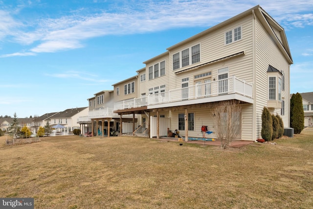 back of house featuring a lawn, a residential view, a wooden deck, a patio area, and central AC