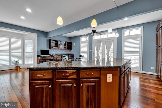 kitchen featuring a wealth of natural light, dark wood-style flooring, and decorative light fixtures