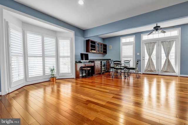 living room with ceiling fan, built in desk, and wood finished floors