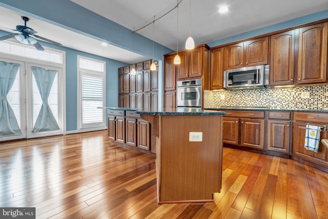 kitchen with stainless steel appliances, a kitchen island, hardwood / wood-style floors, and tasteful backsplash