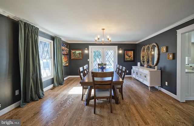 dining space featuring baseboards, ornamental molding, wood finished floors, and an inviting chandelier