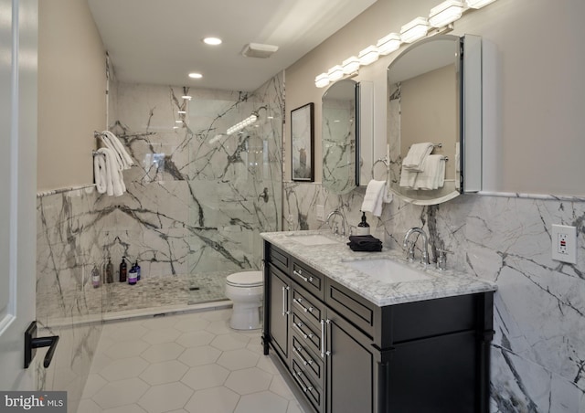 full bathroom featuring a marble finish shower, a sink, tile walls, and toilet