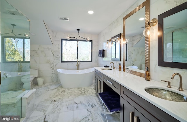 bathroom featuring marble finish floor, a sink, a freestanding bath, and toilet