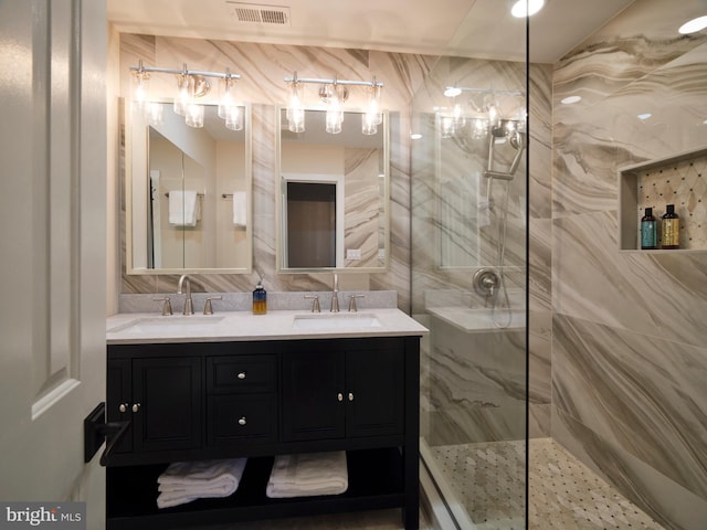 full bathroom featuring a marble finish shower, visible vents, and a sink