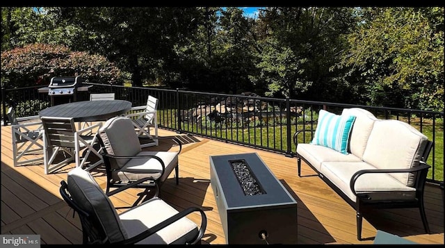 wooden deck with outdoor dining area, an outdoor living space with a fire pit, and area for grilling