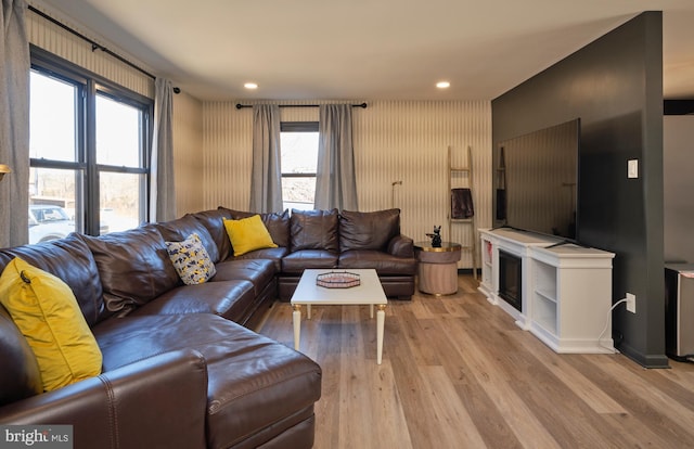 living room featuring light wood-type flooring, a glass covered fireplace, and recessed lighting