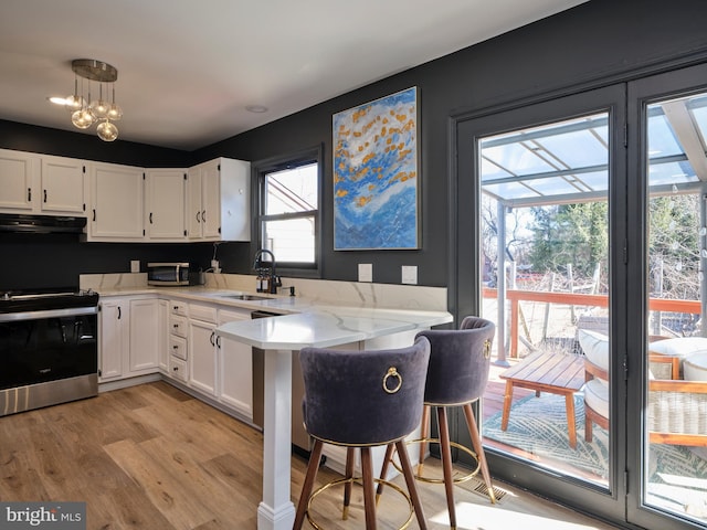 kitchen featuring electric range, a sink, white cabinets, and under cabinet range hood