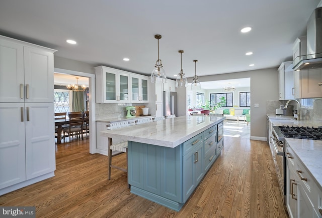 kitchen featuring a kitchen island, appliances with stainless steel finishes, white cabinetry, and a chandelier