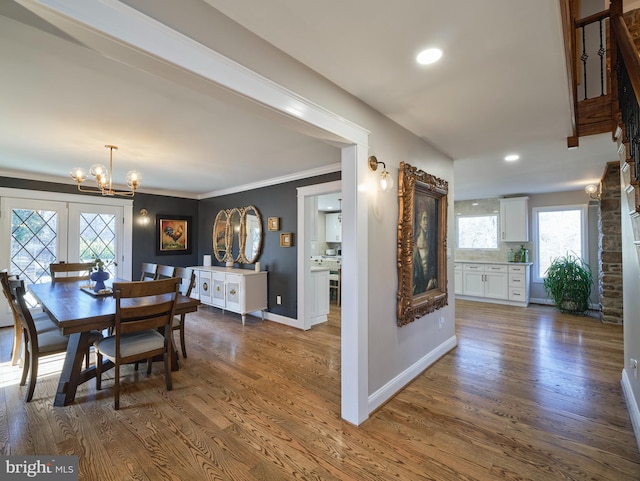 dining space featuring ornamental molding, a notable chandelier, baseboards, and wood finished floors