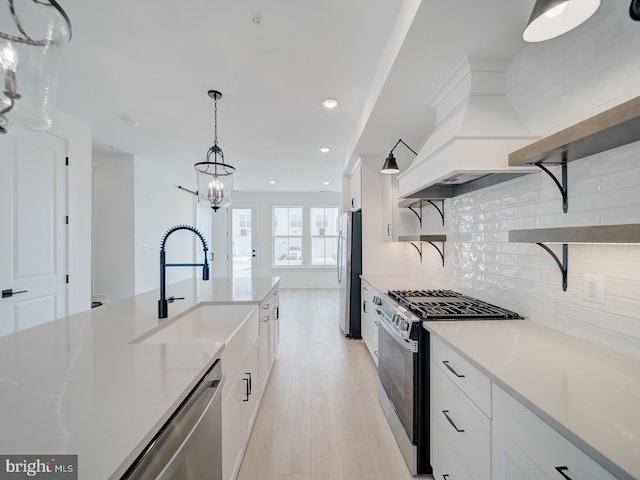 kitchen featuring open shelves, backsplash, appliances with stainless steel finishes, white cabinetry, and a sink