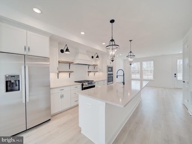 kitchen featuring open shelves, stainless steel appliances, tasteful backsplash, light wood-type flooring, and premium range hood