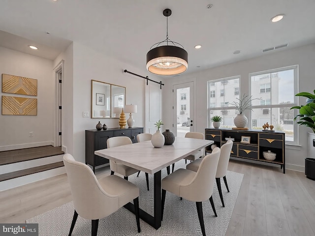 dining area featuring a barn door, recessed lighting, visible vents, baseboards, and light wood finished floors