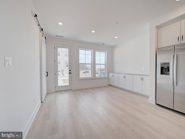 interior space featuring a barn door, visible vents, baseboards, light wood-style floors, and recessed lighting