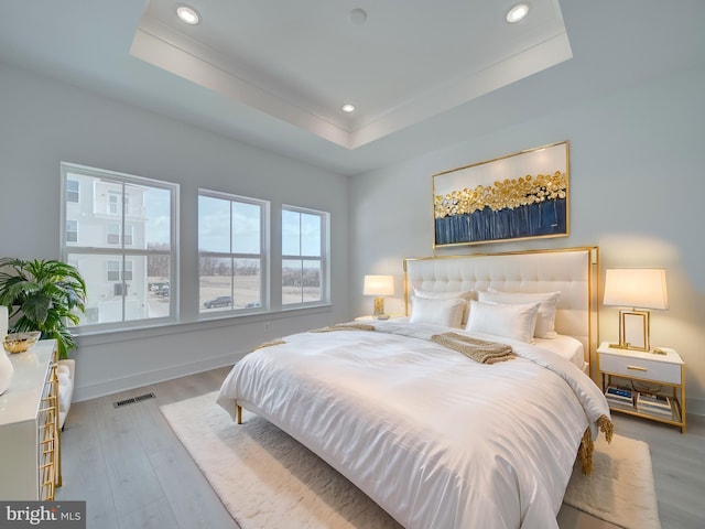 bedroom featuring wood finished floors, a raised ceiling, visible vents, and recessed lighting