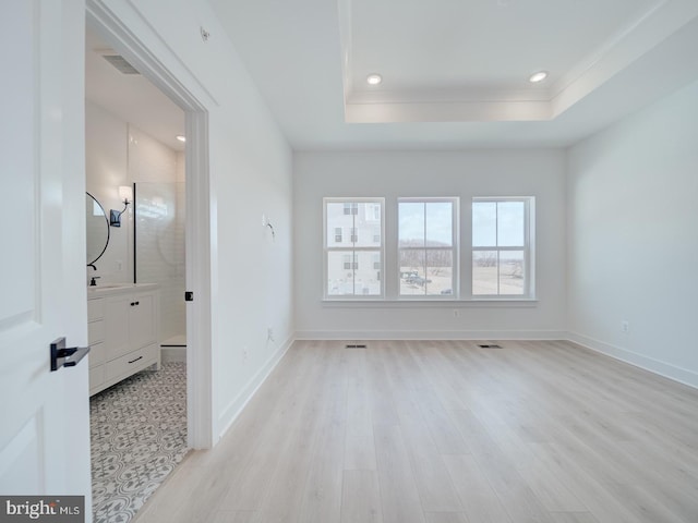 interior space with light wood-style flooring, recessed lighting, visible vents, baseboards, and a raised ceiling