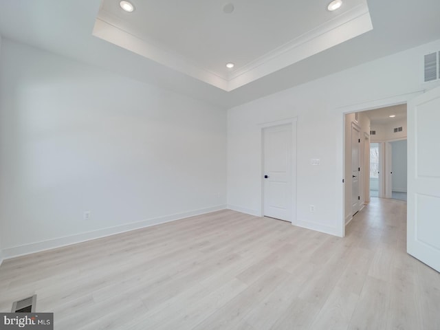 unfurnished room with recessed lighting, visible vents, baseboards, light wood finished floors, and a raised ceiling