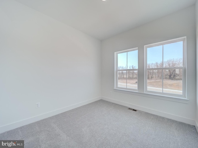 empty room with carpet, visible vents, and baseboards