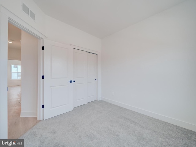 unfurnished bedroom featuring a closet, visible vents, light carpet, and baseboards