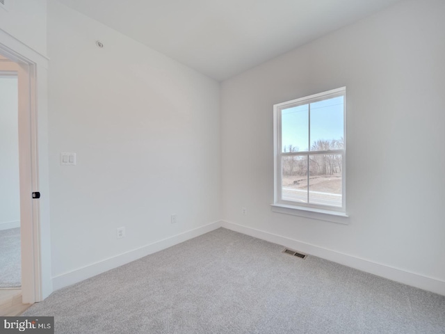 empty room featuring light carpet, baseboards, and visible vents