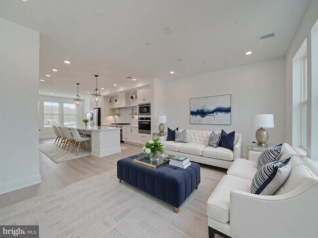 living area with recessed lighting, visible vents, light wood-style flooring, and baseboards